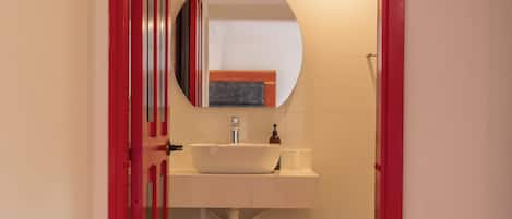 A bathroom with a white sink, a mirror, and a red door.