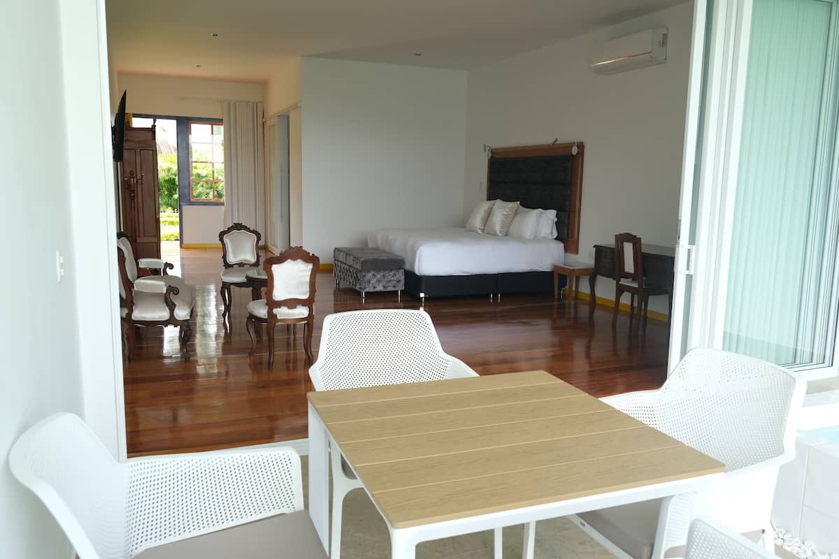 A hotel room with a bed, a dining table, and a seating area.