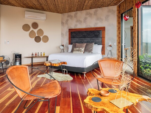 Une chambre moderne avec un grand lit, un plancher en bois et une vue sur la verdure environnante.
