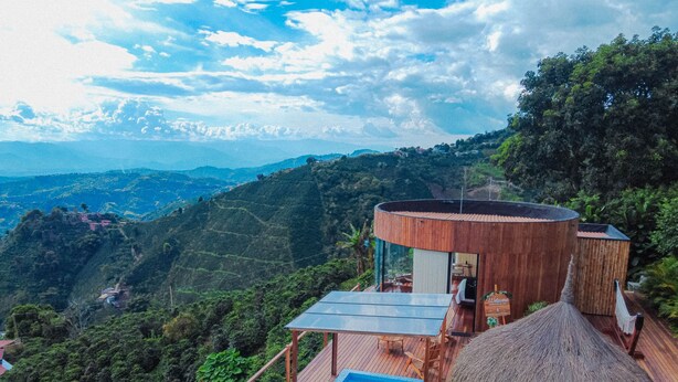 A modern villa with a glass-enclosed infinity pool, wooden deck, and a thatched-roof structure. - Atardeceres del cafe (Manizales)