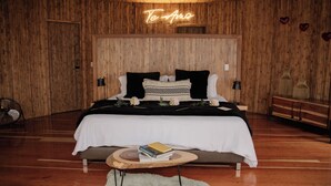 A wooden-paneled bedroom with a bed, bedside tables, a neon sign, and a fan. - Atardeceres del cafe (Manizales)