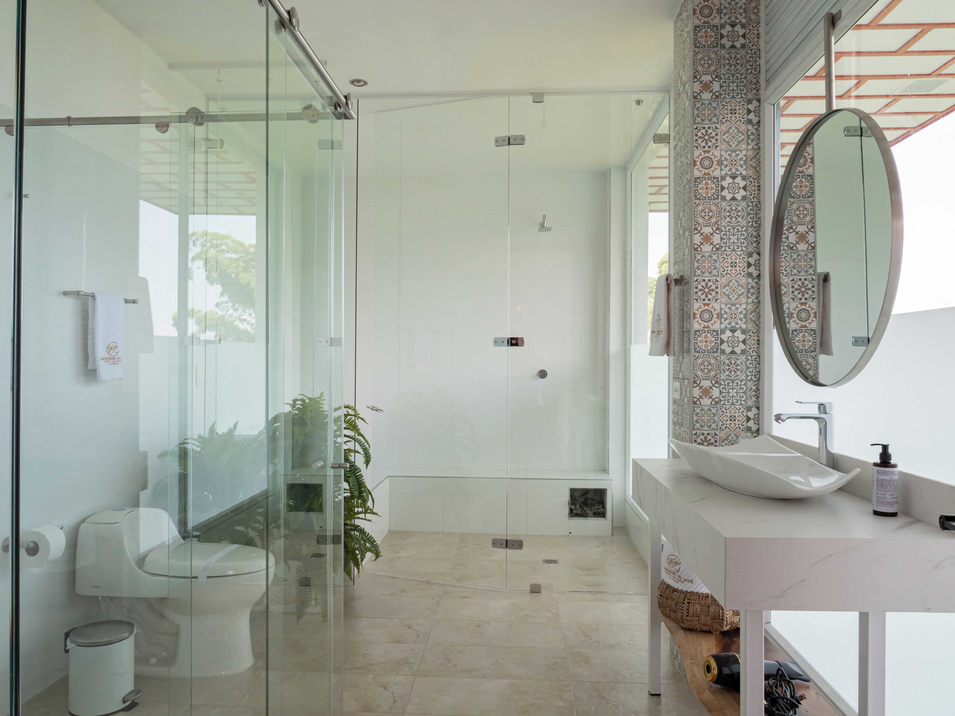 A modern bathroom with a glass-enclosed shower, a white sink, and a decorative mirror.