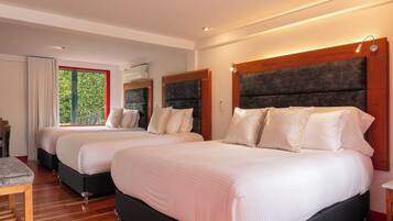 Een moderne hotelkamer met twee bedden, houten vloeren en een groot raam met uitzicht op groen.