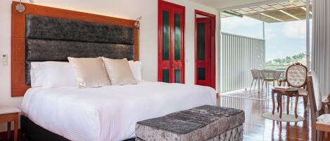 A bedroom with a large bed, a bench, a table, and chairs.