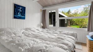 A bedroom with a large bed, a window with a view of greenery, and a painting on the wall. - Cozy home in Idestrup with WiFi (Idestrup)