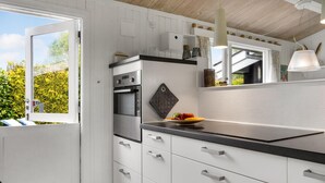 A modern kitchen with white cabinetry, a black countertop, and a built-in oven. - Cozy home in Idestrup with WiFi (Idestrup)