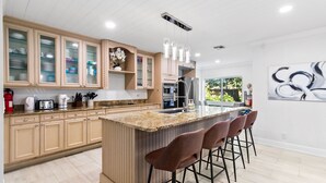 Una cocina moderna con una isla grande, armarios de madera y taburetes de bar.