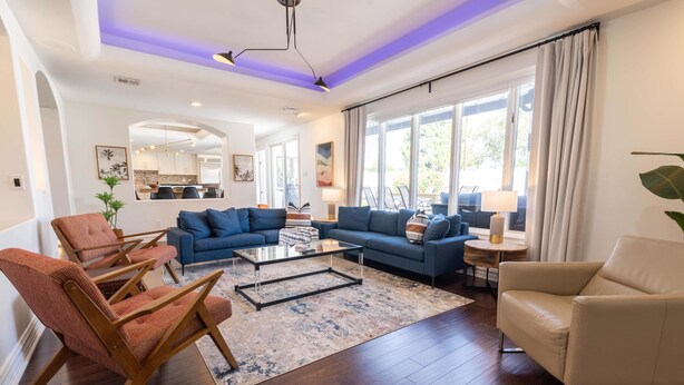 A spacious living room with a blue sofa set, a beige armchair, and a coffee table.