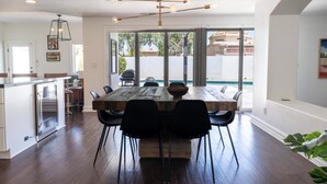 A modern kitchen with a wooden island, black chairs, and a large dining table.