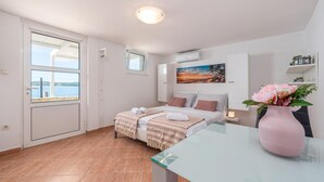A bedroom with a bed, a glass table, a pink vase with flowers, a painting, and a view of the sea through a window. - Amazing apartment in Bibinje with house sea view (Bibinje)