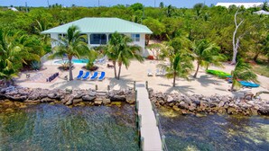 A beachfront property with a pool, lounge chairs, and a dock leading to a rocky shoreline. - MILLION DOLLAR VIEW very private 4 bedroom resort with pool, pier, kayaks, spa (Marathon)