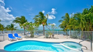 A swimming pool with blue water, surrounded by palm trees and a white fence. - MILLION DOLLAR VIEW very private 4 bedroom resort with pool, pier, kayaks, spa (Marathon)
