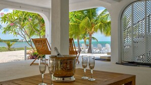 A wooden table with a metal bucket and four wine glasses, overlooking a beach with palm trees and a clear view of the ocean. - MILLION DOLLAR VIEW very private 4 bedroom resort with pool, pier, kayaks, spa (Marathon)