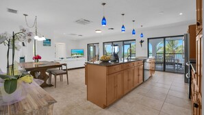 A spacious kitchen with a central island, wooden cabinets, and a dining area with chairs. - MILLION DOLLAR VIEW very private 4 bedroom resort with pool, pier, kayaks, spa (Marathon)