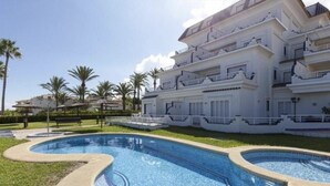 Un grand hôtel moderne doté d’une piscine, de nombreux balcons et d’un jardin bien entretenu.