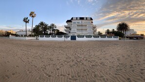 Un hôtel situé en bord de mer, avec un bâtiment à plusieurs étages, des palmiers et une vue dégagée sur l’océan.