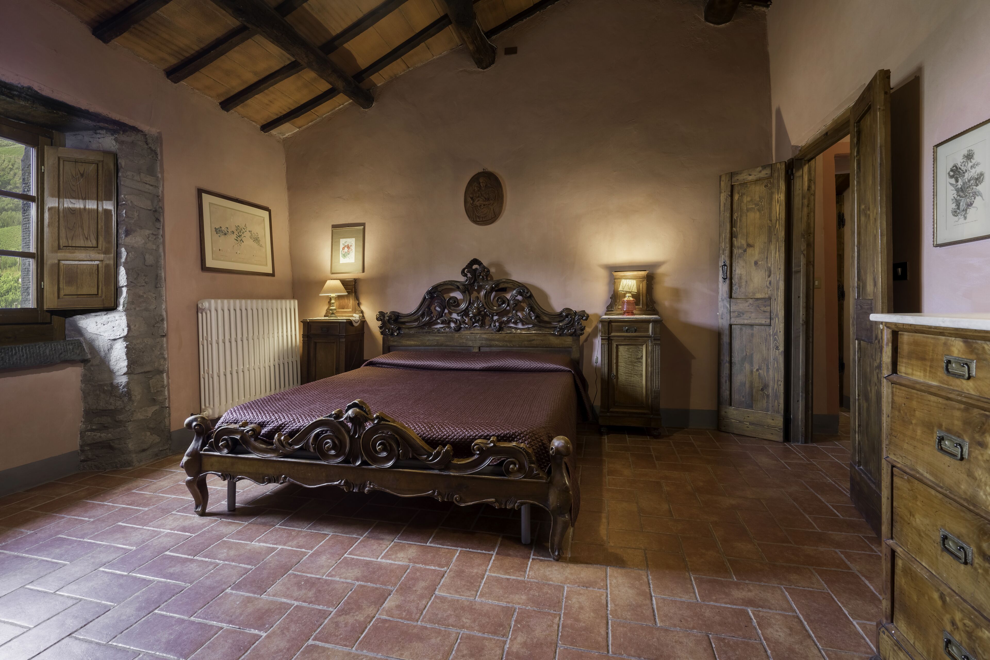 A bedroom with a large ornate bed, a stone wall, and a wooden ceiling.