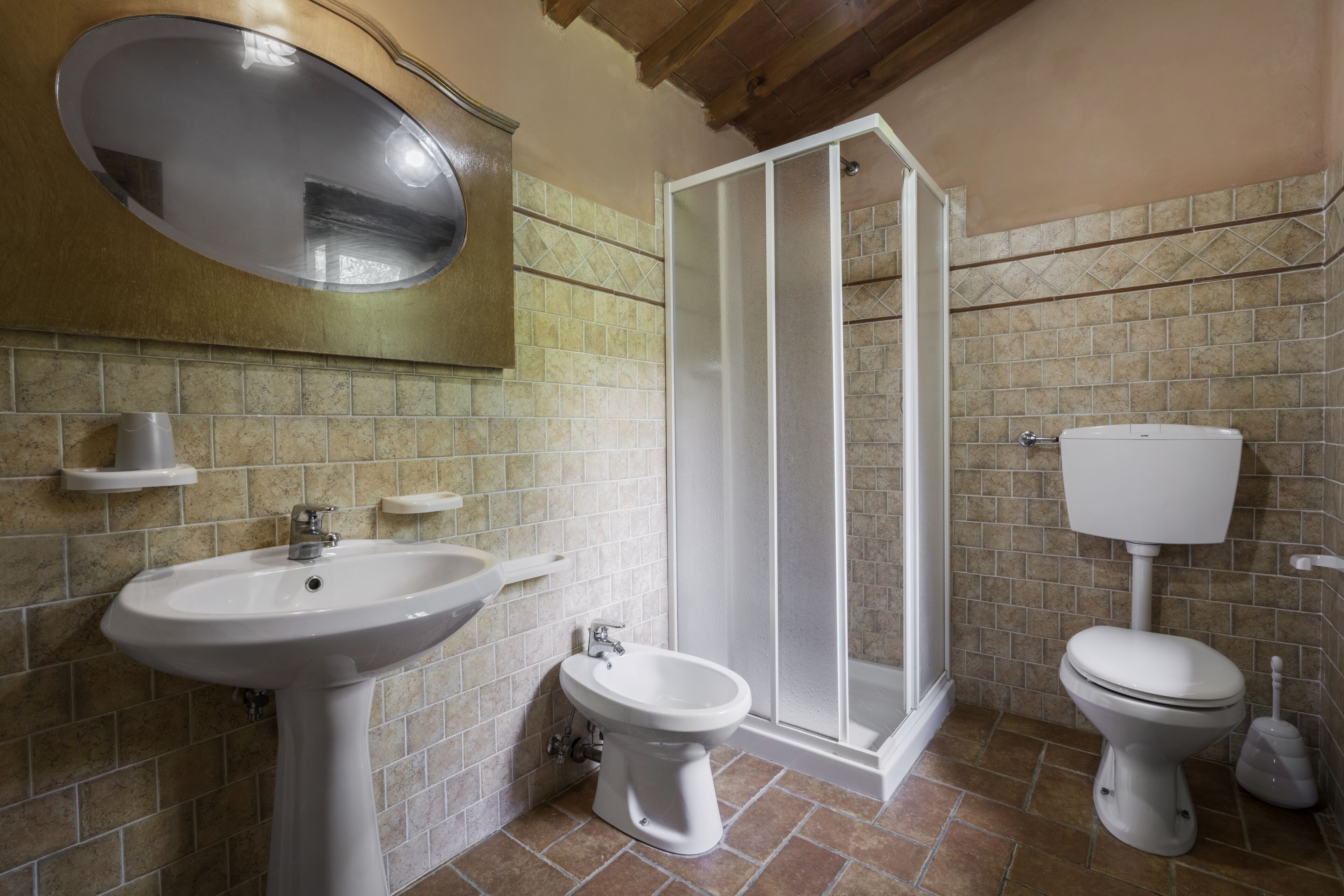 Une salle de bain comprenant un lavabo sur colonne, un bidet, des toilettes et une douche  à parois de verre.