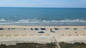 A beach with umbrellas, sun loungers, and a lifeguard tower.