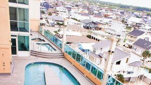 A swimming pool with a 3-foot depth marker, surrounded by a building with large windows and a view of a residential area.