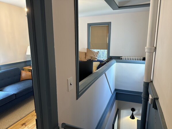 A room with a bed, a window with a view, a radiator, and a blue wall. - Village Apt (Saugerties)