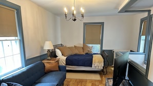 Une chambre à coucher avec un lit, un canapé bleu, un plancher en bois et un lustre.