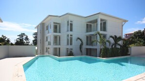 A modern multi-story building with a swimming pool in front. - Private Garden Condo - 5 min from the Beach (Koh Samui)