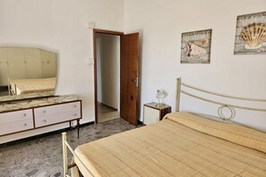 A bedroom with a bed, a dresser, a mirror, and a door leading to another room.
