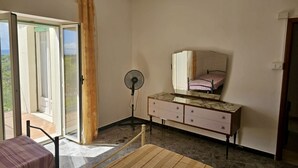 A room with a bed, a dresser, a fan, and a sliding glass door leading to an outdoor area. - S320 - Sirolo, one bedroom apartment with breathtaking view (La Madonnina)