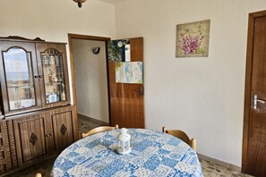 A dining area with a round table, chairs, a cabinet, and a door leading to another room.