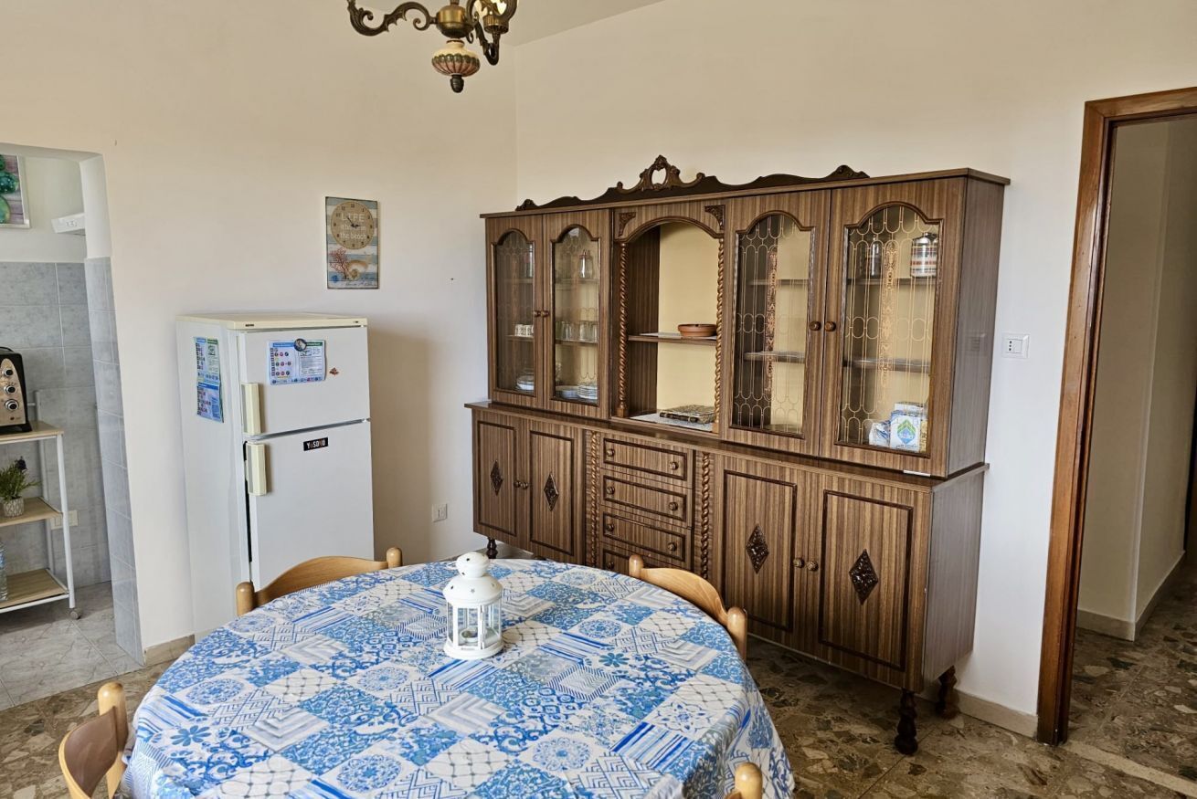 Un coin repas comprenant une table ronde, des chaises, un réfrigérateur blanc et un meuble en bois doté de portes en verre.