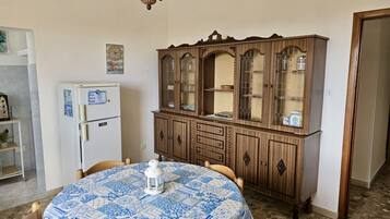 Un coin repas comprenant une table ronde, des chaises, un réfrigérateur blanc et un meuble en bois doté de portes en verre.