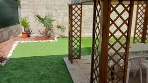 A patio area with a wooden lattice structure, a small table, and chairs. - S319 - Sirolo, three-room apartment with sea view and garden (La Madonnina)
