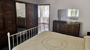 A bedroom with a bed, a dresser, a mirror, and a door leading to an outdoor area. - S319 - Sirolo, three-room apartment with sea view and garden (La Madonnina)