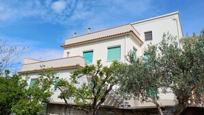 A two-story building with a white facade, green shutters, and a red-tiled roof. - S319 - Sirolo, three-room apartment with sea view and garden (La Madonnina)