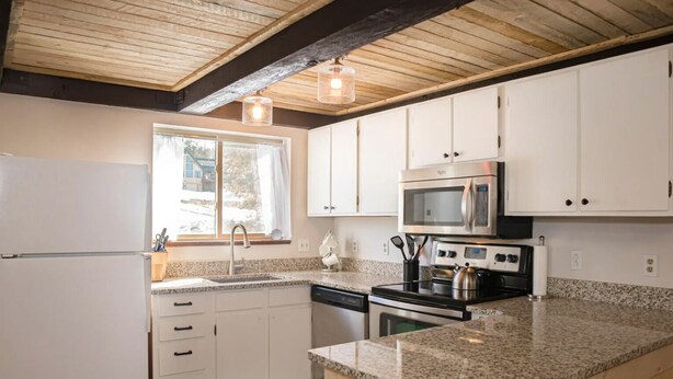 A kitchen with white cabinets, a stainless steel microwave, a stove, and a dishwasher. - Dog-friendly condo close to Winter Park shuttle with pool, hot tub, tennis, gym (Fraser)