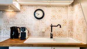 Une cuisine équipée d’un évier, d’une horloge et d’une machine à café.