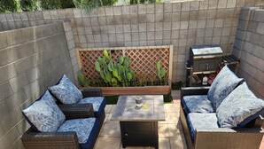 A patio with wicker furniture, a table, and a grill.