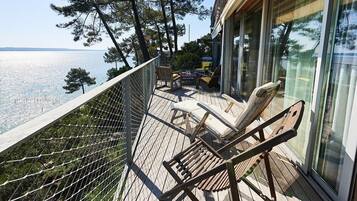 A wooden deck with outdoor furniture, overlooking a body of water.