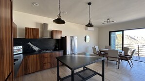 A modern kitchen with wooden cabinets, a black countertop, and a stainless steel refrigerator.