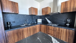 A modern kitchen with wooden cabinets, a black marble countertop, a built-in stove, and a coffee maker.