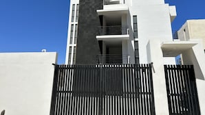 A modern multi-story building with a prominent vertical black and white facade, balconies, and a gated entrance.