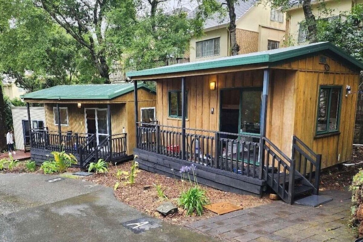 A wooden cabin-style building with a porch and a staircase.