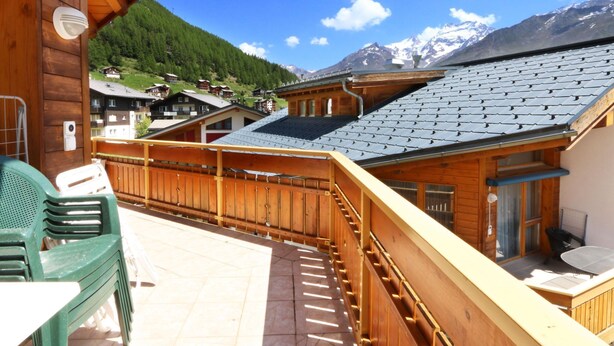 Un chalet en bois doté d’un balcon donnant sur un paysage montagneux.