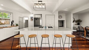 A spacious kitchen with a large island, four bar stools, and a modern pendant light. - Stunning vacation rental offering unique city and beach views (Clontarf)