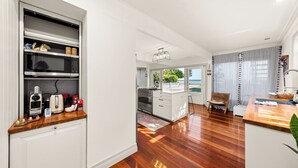 A modern kitchen with white cabinets, a wooden countertop, and a view of the sea through large windows. - Stunning vacation rental offering unique city and beach views (Clontarf)