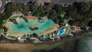 An aerial view of a coastal resort with a clear turquoise lagoon, surrounded by lush greenery and a stone wall. - Stunning vacation rental offering unique city and beach views (Clontarf)