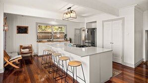 A modern kitchen with a large island, bar stools, a stainless steel refrigerator, and a chalkboard sign. - Stunning vacation rental offering unique city and beach views (Clontarf)