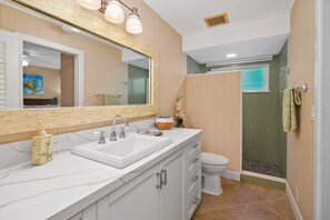 A bathroom with a white vanity, a large mirror, a shower enclosure, and a toilet. - Hale Walelia by Alekona Kauai: Poipu Kai 3 Bedroom w Pool, Spa, steps to Shipwreck Beach (Koloa)
