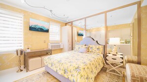 A bedroom with a large bed, a dresser, a vanity, and a mirror.